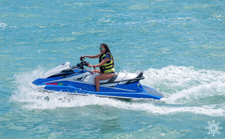 image shows a person riding a blue and white jet ski in the ocean